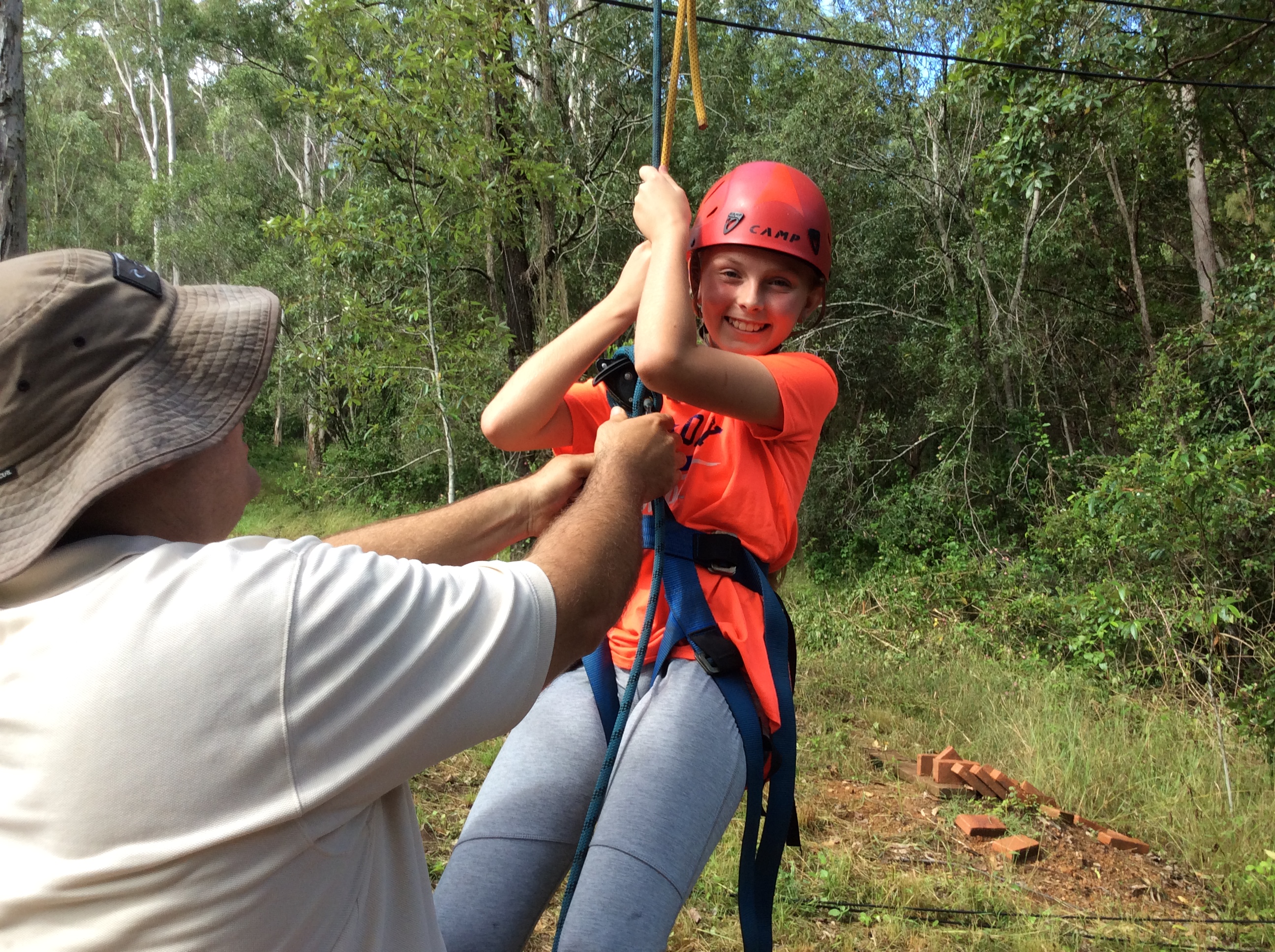 Student taking part in an outdoor adventure activity with safety equipment.